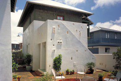 Exemple d'une façade de maison bord de mer en stuc à un étage.