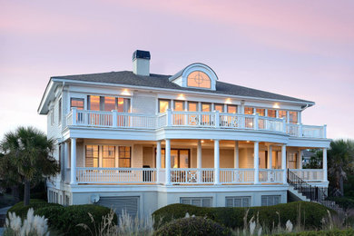 Example of a beach style gray two-story house exterior design in Charleston with a hip roof and a shingle roof