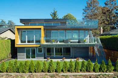 Exemple d'une façade de maison grise moderne en panneau de béton fibré de taille moyenne et à un étage avec un toit plat.