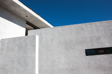Modelo de fachada de casa blanca moderna pequeña de dos plantas con revestimiento de estuco y tejado plano