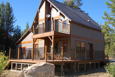 Imagen de fachada de casa gris rural de tamaño medio de dos plantas con revestimiento de madera, tejado a dos aguas y tejado de metal
