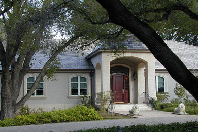 Cette photo montre une très grande façade de maison grise rétro en stuc de plain-pied avec un toit à quatre pans.