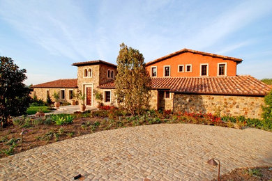 Foto de fachada de casa naranja mediterránea de tamaño medio de dos plantas con revestimientos combinados, tejado a dos aguas y tejado de teja de barro