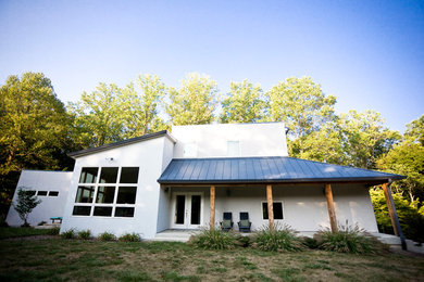 Example of a mid-sized minimalist white two-story stucco house exterior design in Indianapolis with a shed roof and a metal roof