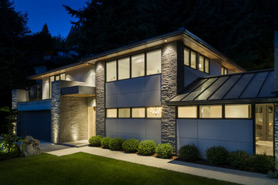 Cette image montre une grande façade de maison grise minimaliste en pierre à un étage.