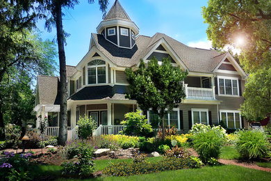 Ejemplo de fachada de casa beige de estilo americano grande de tres plantas con revestimiento de aglomerado de cemento, tejado a dos aguas y tejado de teja de madera