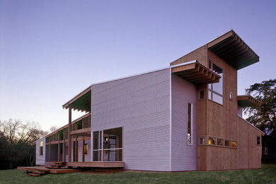 Cette photo montre une petite façade de maison grise moderne à un étage avec un revêtement mixte et un toit à deux pans.