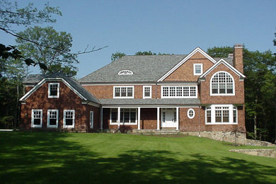 Imagen de fachada de casa marrón de estilo americano grande de dos plantas con tejado a dos aguas y tejado de teja de madera