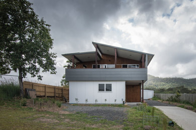 Bild på ett mellanstort funkis grått hus, med två våningar, fiberplattor i betong, pulpettak och tak i metall