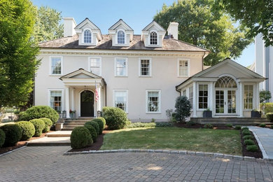 Inspiration for a large timeless beige three-story stucco house exterior remodel in New York with a shingle roof