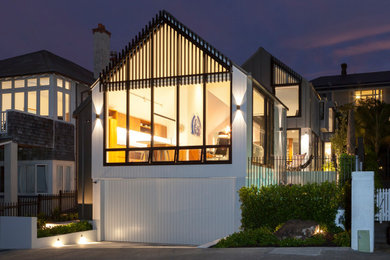 Foto de fachada de casa blanca costera de dos plantas con revestimientos combinados y tejado a dos aguas