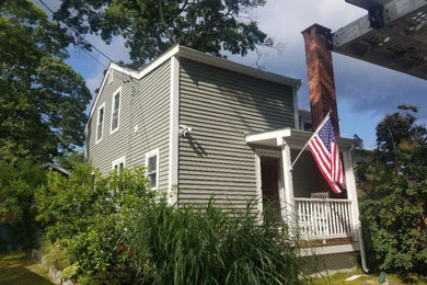 Mittelgroßes, Zweistöckiges Einfamilienhaus mit Vinylfassade, grüner Fassadenfarbe, Satteldach und Schindeldach in Boston
