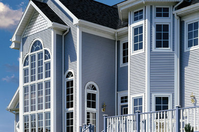 Imagen de fachada de casa azul tradicional de tamaño medio de dos plantas con revestimiento de vinilo, tejado a dos aguas y tejado de teja de madera