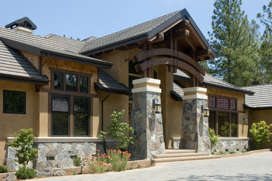 Ejemplo de fachada de casa beige de una planta con revestimientos combinados y tejado de teja de barro