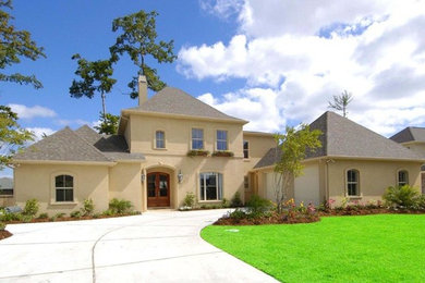 Large tuscan beige two-story stucco house exterior photo in New Orleans with a hip roof and a shingle roof