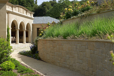 Modelo de fachada beige mediterránea grande de una planta con revestimiento de piedra y tejado a cuatro aguas