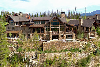 Стильный дизайн: трехэтажный, огромный, деревянный, коричневый частный загородный дом в стиле рустика с крышей из смешанных материалов - последний тренд