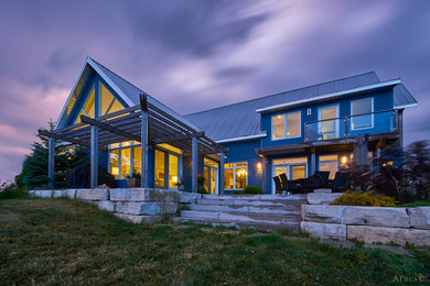 Diseño de fachada de casa azul campestre grande de dos plantas con revestimiento de madera, tejado a dos aguas y tejado de metal