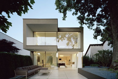 Diseño de fachada de casa beige moderna de tamaño medio de dos plantas con revestimiento de vidrio y tejado plano