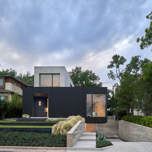 Imagen de fachada de casa negra, minimalista, de tres plantas, con revestimiento de hormigón y tejado plano