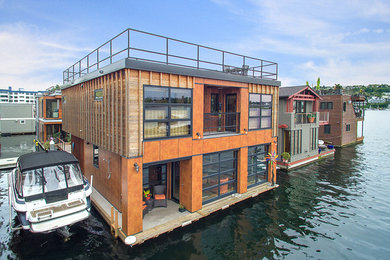 This is an example of an expansive industrial two floor detached house in Seattle with wood cladding, a flat roof and an orange house.