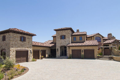 Cette photo montre une grande façade de maison beige méditerranéenne en pierre à un étage avec un toit à deux pans et un toit en tuile.