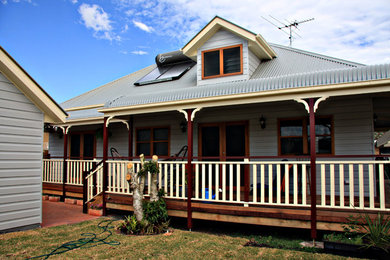 Ejemplo de fachada de casa gris tradicional de tamaño medio de una planta con revestimiento de vinilo, tejado a cuatro aguas y tejado de metal
