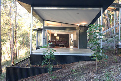 Идея дизайна: одноэтажный, маленький, черный дом в стиле модернизм с облицовкой из металла и плоской крышей для на участке и в саду