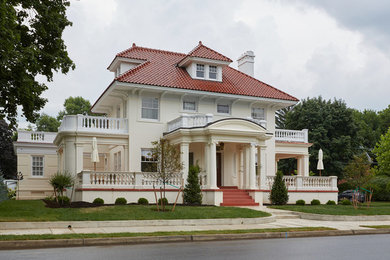 Diseño de fachada de casa blanca tradicional grande de tres plantas con revestimiento de estuco, tejado a la holandesa y tejado de teja de barro