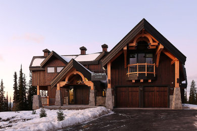 Immagine della villa grande marrone rustica a tre piani con rivestimento in legno, tetto a capanna e copertura a scandole
