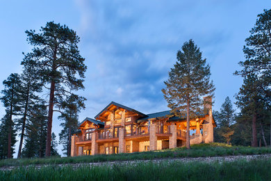 Photo of a large rustic two floor house exterior in Denver with wood cladding.