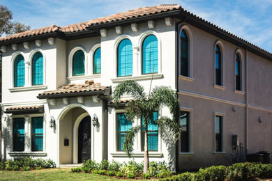 Mid-sized tuscan beige two-story stucco house exterior photo in Tampa with a hip roof and a tile roof