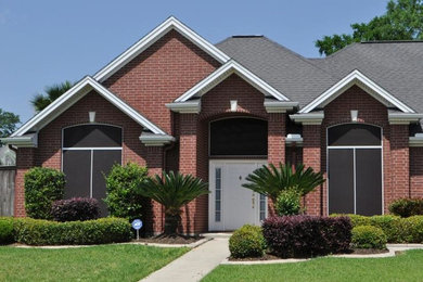 Huge traditional red one-story brick exterior home idea in Austin