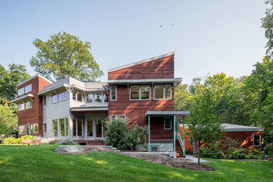 Foto della villa grande marrone contemporanea a due piani con rivestimenti misti, tetto a padiglione e copertura in metallo o lamiera