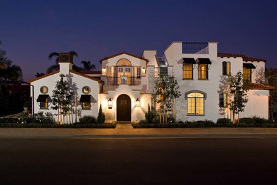 Large tuscan white two-story stucco exterior home photo in Orange County with a tile roof