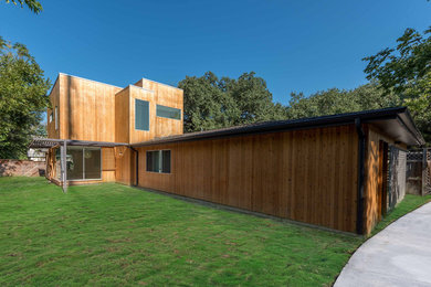 Photo of a large contemporary two floor house exterior in Austin with wood cladding and a flat roof.