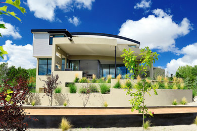 Diseño de fachada de casa beige actual grande de dos plantas con revestimiento de estuco y tejado plano