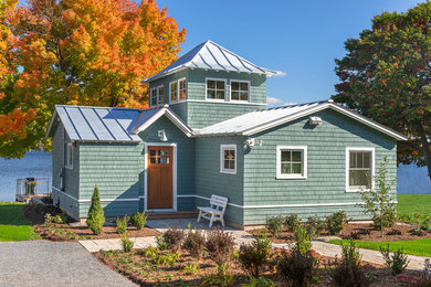 Стильный дизайн: маленький, двухэтажный, деревянный, зеленый дом в морском стиле с двускатной крышей для на участке и в саду - последний тренд