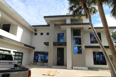 Diseño de fachada de casa beige moderna grande de dos plantas con revestimiento de estuco y tejado plano