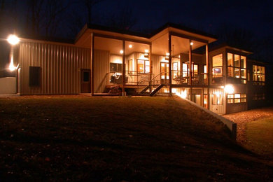 Cette photo montre une façade de maison métallique et beige moderne à un étage et de taille moyenne avec un toit en appentis et un toit en métal.
