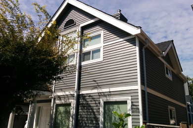 Diseño de fachada de casa gris moderna de tamaño medio de tres plantas con revestimiento de madera, tejado a dos aguas y tejado de teja de madera