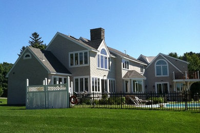 Immagine della facciata di una casa grande grigia american style a due piani con rivestimento in legno e tetto a capanna