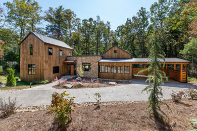 Mountain style brown two-story wood house exterior photo in Other with a metal roof and a gray roof