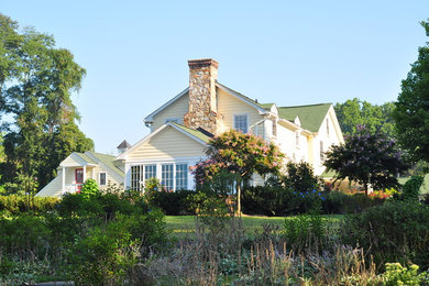 Large elegant yellow three-story concrete fiberboard house exterior photo in Baltimore with a clipped gable roof