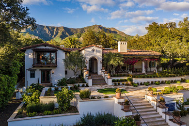 Inspiration for a large mediterranean white two-story stucco exterior home remodel in Santa Barbara with a tile roof