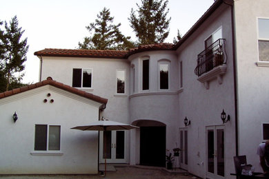 Diseño de fachada blanca mediterránea de dos plantas con revestimiento de estuco y tejado a cuatro aguas