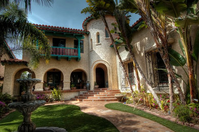 Inspiration for a large mediterranean beige two-story stucco house exterior remodel in Los Angeles with a clipped gable roof and a tile roof