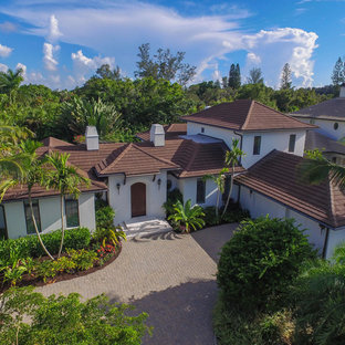 Idee per la facciata di una casa grande bianca tropicale a due piani con rivestimento in stucco e tetto a padiglione