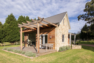 Exemple d'une petite façade de maison nature en bois à un étage avec un toit à deux pans et un toit en métal.