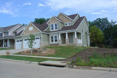 Example of a mid-sized arts and crafts green two-story vinyl exterior home design in Cedar Rapids with a clipped gable roof